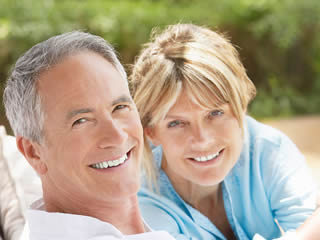 Mature couple smiling with dental implants in mouth